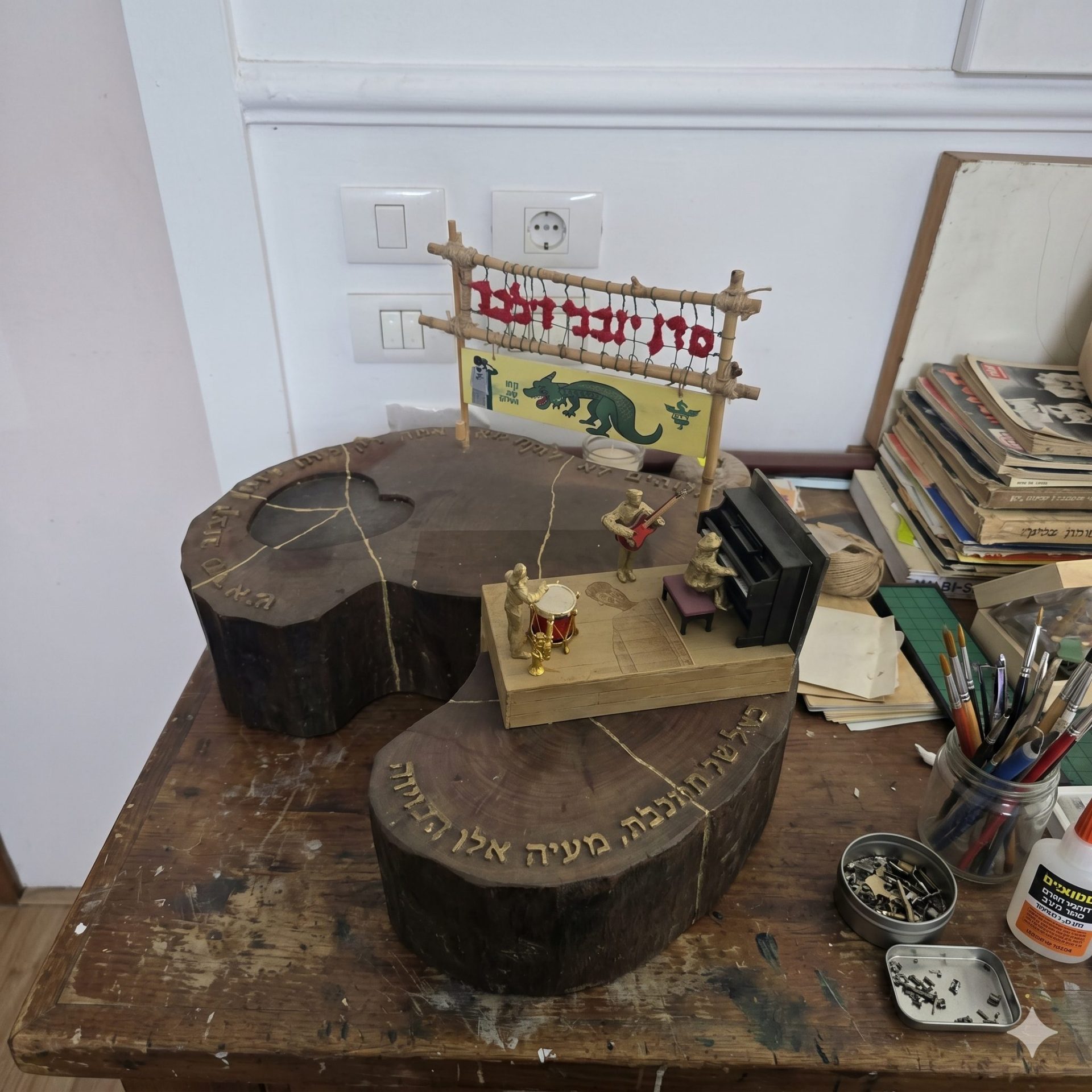 יצירת אמנות מעץ בצורת מפת ארץ ישראל שבורה ומאוחה בזהב עם כיתוב חרוט, לצד דגל ישראל קטן.